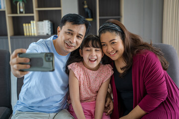 Cheerful family with daughter laughing taking selfie together on phone,Smiling parents together with cute little girl child pose taking selfie picture.