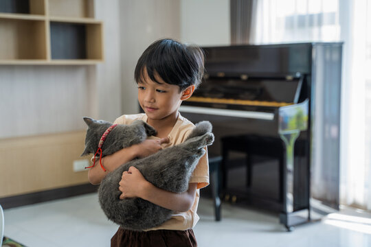 Asian child playing with cat at home.