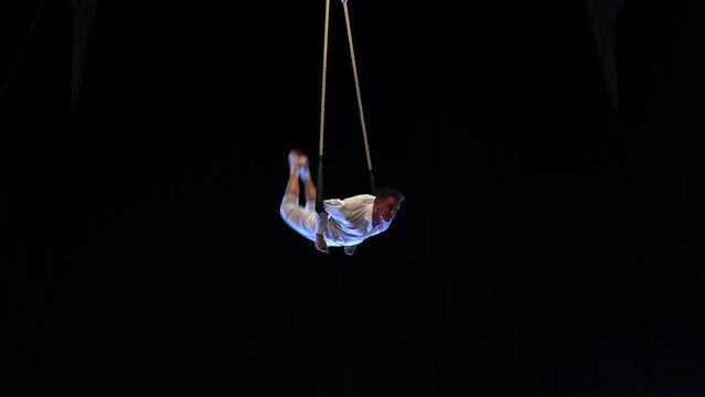 Muscular male air circus artist performances with dance trapeze 