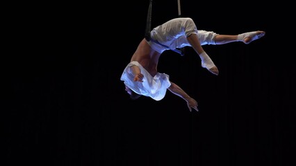 Muscular male air circus artist performances with dance trapeze 