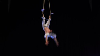 Muscular male air circus artist performances with dance trapeze 