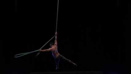 Muscular and fit circus artist perform on aerial rope on high altitude