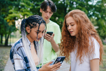 Three caucasian modern teenagers pleased to get many positive reactions on their internet posts. Creating a video for the internet using a smartphone