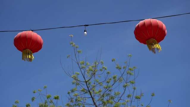 Two red Chinese lantern hanging at wire in blue sky