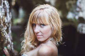 Naklejka premium beautiful blonde girl in a white dress with a corset in a deep dark cave