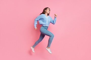 Fototapeta na wymiar Profile side full length photo of attractive cheerful cute girl running in air clenching fists look at empty space isolated on pink color background