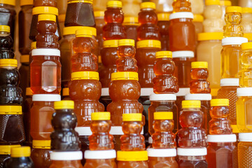 There are many jars of organic, natural honey on the counter for sale. Different honey, different colors in plastic cans are ready for sale at the honey fair. Nuts filled with honey. 