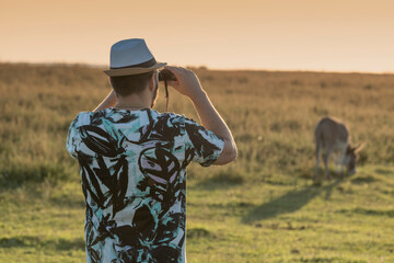 The young birdwacher with binocular obseving bird migration on the sunset pasture