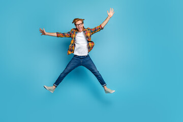 Obraz premium Photo of funky handsome good mood guy open mouth dressed plaid shirt jumping impressed hands to side isolated on blue color background