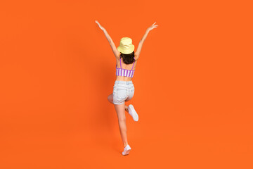 Full length photo of funny carefree lady purple swimwear walking rising arms hands isolated orange color background