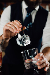 close up of barmen adding ice in glass