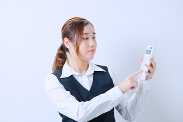 左手で持った電卓を右手で押す若いOL