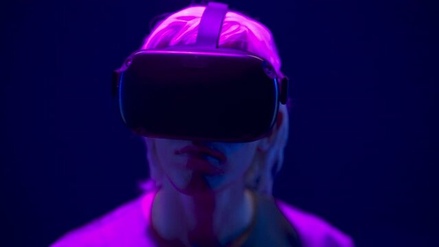 Focused man watching VR headset in neon light closeup. Guy enjoying 3d movie