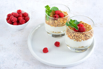 healthy dessert with granola, yoghurt and raspberries in glasses, close-up