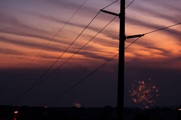 power lines at sunset with fireworks
