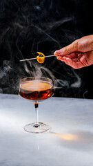Smokey manhattan on marble being garnished