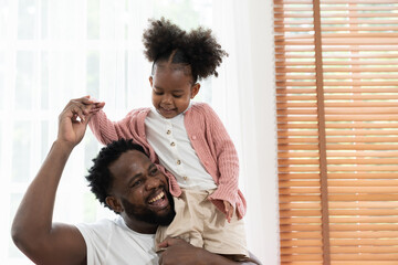 Father and daughter playing together at home. Happy African American small girl kid playing with dad