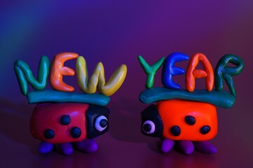 Two ladybugs and the inscription new year. A festive event. Christmas decorations. Purple background.