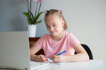 Girl with Down Syndrome doing homework at home, getting ready to go back to school