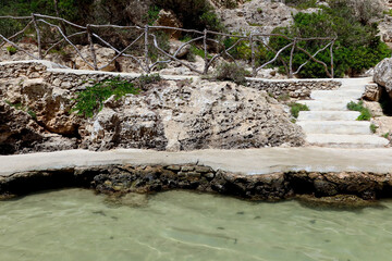 Cala en Forcat, Menorca (Minorca), Spain. Cala en Forcat - unique place surrounded by rocky cliffs and pines with shallow waters and two small beaches. Rock shelves and typical Menorcan fencing system