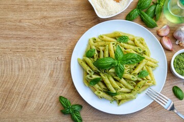 Penne pasta with pesto sauce on plate with wooden table background.Easy and healthy vegetarian Italian food.Top view.Copy space