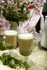 Home made matcha green tea in two glass cups with mint and lemon balm leaves, summer breakfast concept.