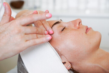 Pretty yanog woman receiving face massage, closeup photo. Beauty and health procedures in a beauty salon