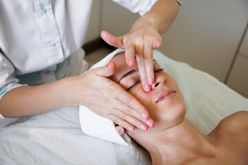 Obraz na płótnie Canvas Pretty yanog woman receiving face massage, closeup photo. Beauty treatments. Beautician