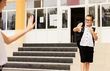 Mother son saying her goodbye for the day. He is very happy that he is going to primary school.