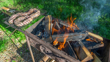 Tasty homemade sausage made of beaver meat cooking on grill. Beaver meat sausages are cooked on coals.