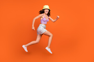 Full length photo of excited pretty lady purple swimwear jumping high running empty space isolated orange color background