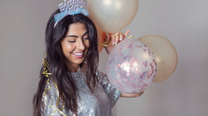 Beautiful woman with Birthday Girl Tiara and shiny dress holding party balloons and laughing  . Birthday party concept  © boryanam