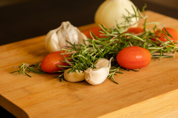 close-ups of tomatoes, rosemary and garlic on wooden board
