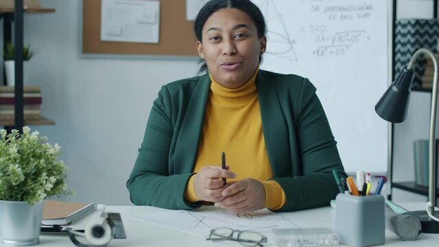 Portrait of African American woman teaching geometry online showing drawings speaking and looking at camera. Home schooling and distant education concept.