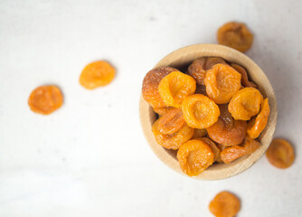 dried apricots in a wooden bowl on a gray concrete table, dried fruits