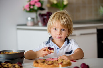 Cute little toddler child, eating homemade plum pie at home