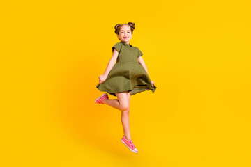 Full size portrait of active energetic person jumping have fun hold dress isolated on yellow color background
