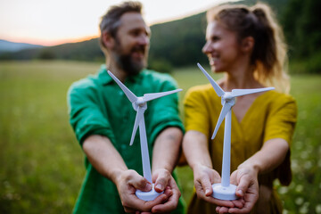 Couple standing in nature with model of wind turbine. Concept of ecology future and renewable...