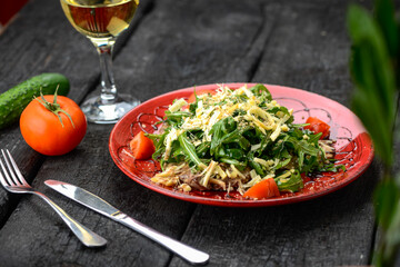 salad with meat, cheese, arugula and tomatoes in a red plate
