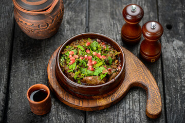 baked meat in a pan with greens and pomegranate berries
