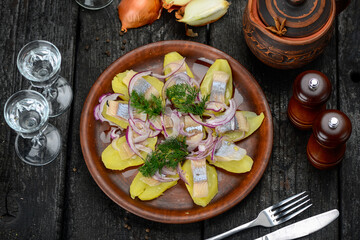 fillet on potatoes with onions and greens in a clay plate on the table with vodka

