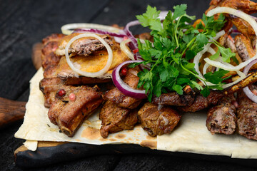 grilled meat with vegetables on a wooden board on a black background macro photo

