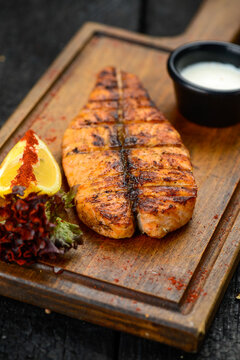 large salmon fillet grilled on a wooden board macro photo
