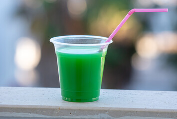 Green cocktail in a glass with a straw.