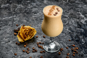 coffee drink in a glass decorated with coffee beans on a table with a rose
