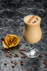 coffee drink in a glass decorated with coffee beans on a table with a rose vertical photo
