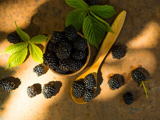 fresh blackberries in a wooden bowl and spoon on an old table