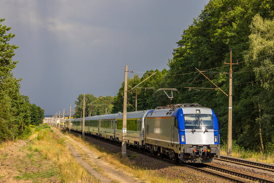 Nowoczesna elektryczna niebiesko-srebrna lokomotywa z pociągiem ekspresowym ucieka przed burzą