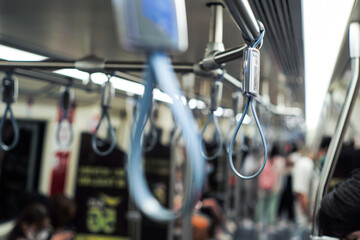 Selective focus on the handrail inside the subway train with blurred group of passengers in background