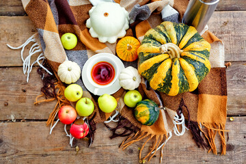 The concept of autumn nature. Lying vegetables on the background of a wooden texture. Yellow and orange pumpkin, red and green apples, tea and autumn maple leaves. Thanksgiving Day Background